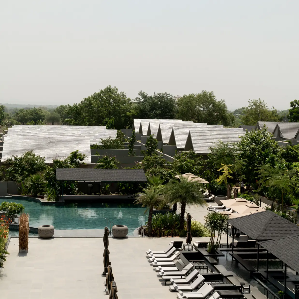 The ARTH estate from above: villa rooftops among trees around a long pool