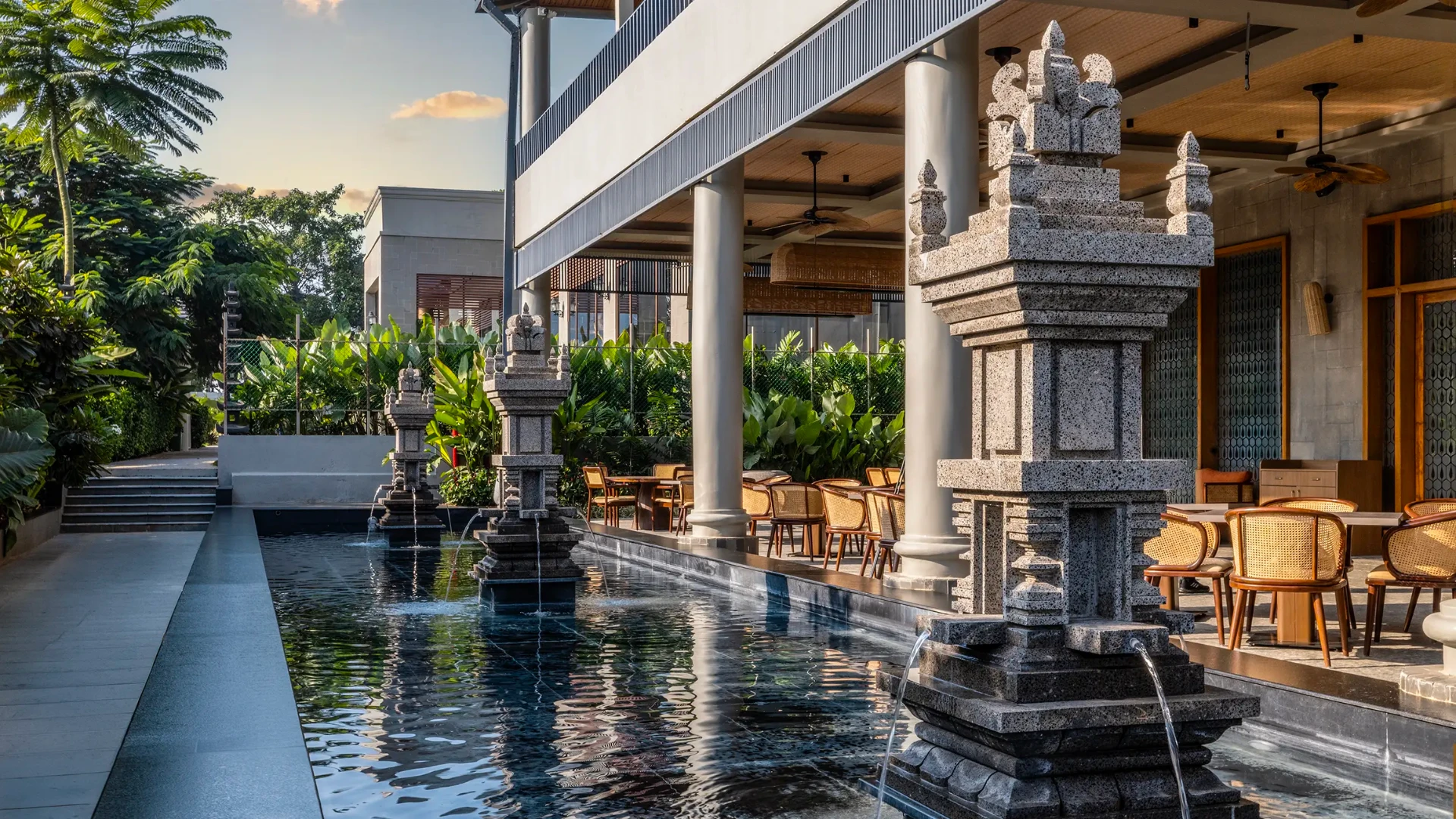 A dining terrace beside water and carved stone lanterns
